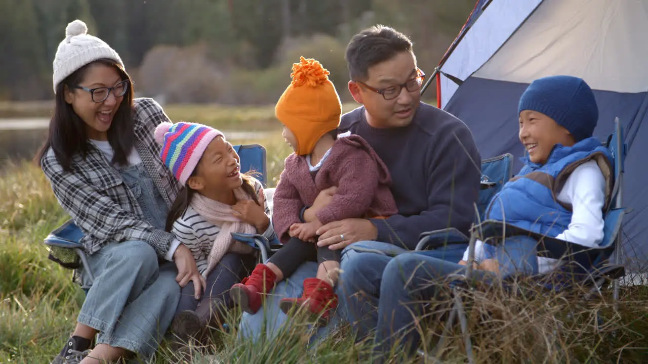 Asian family on a camping trip talking outside their tent