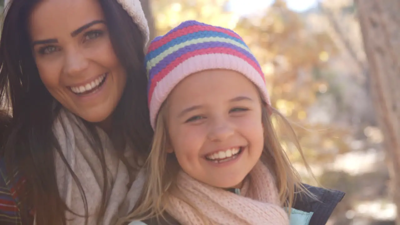 Female parents and daughter in a forest looking to camera