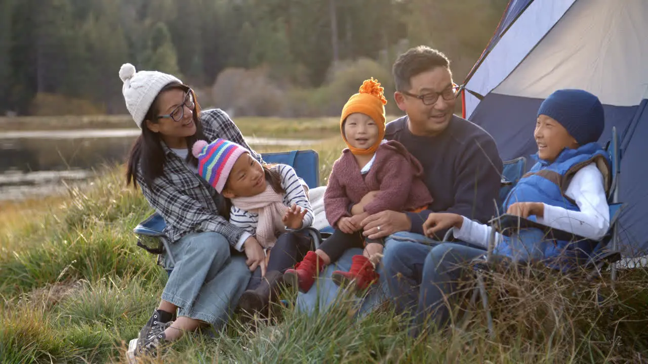 Asian family on a camping trip relaxing outside their tent