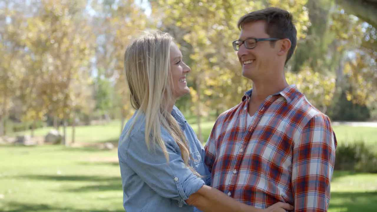 Caucasian couple embracing in a park and looking to camera