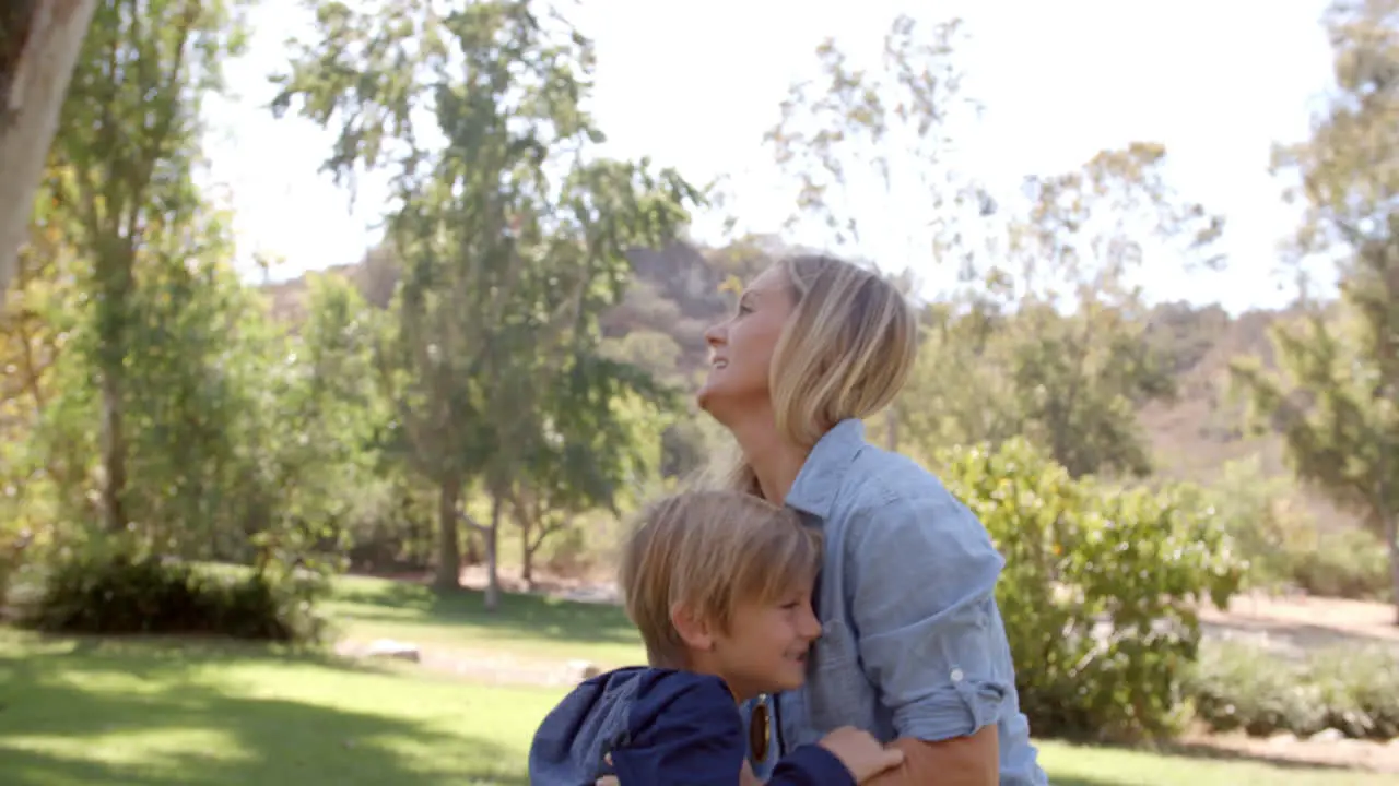 Mother lifting up her son and embracing in a park