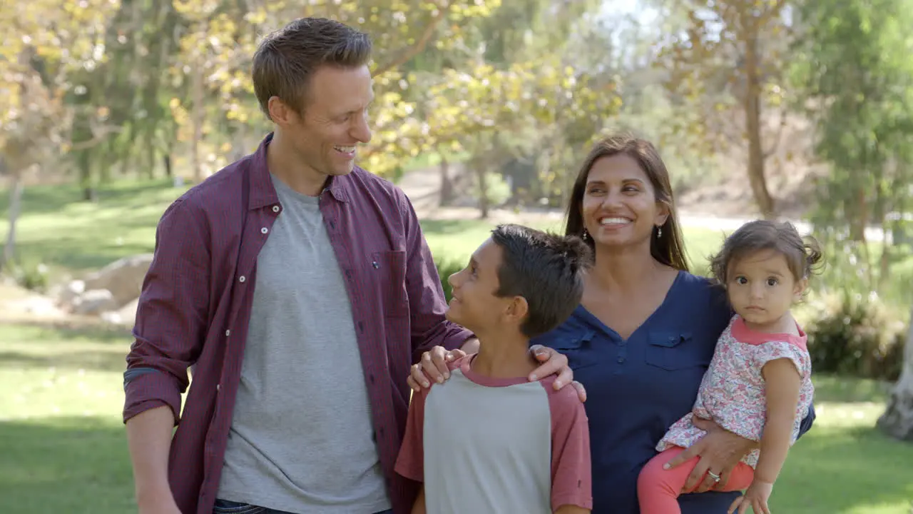 Happy mixed race family walking into focus together in park