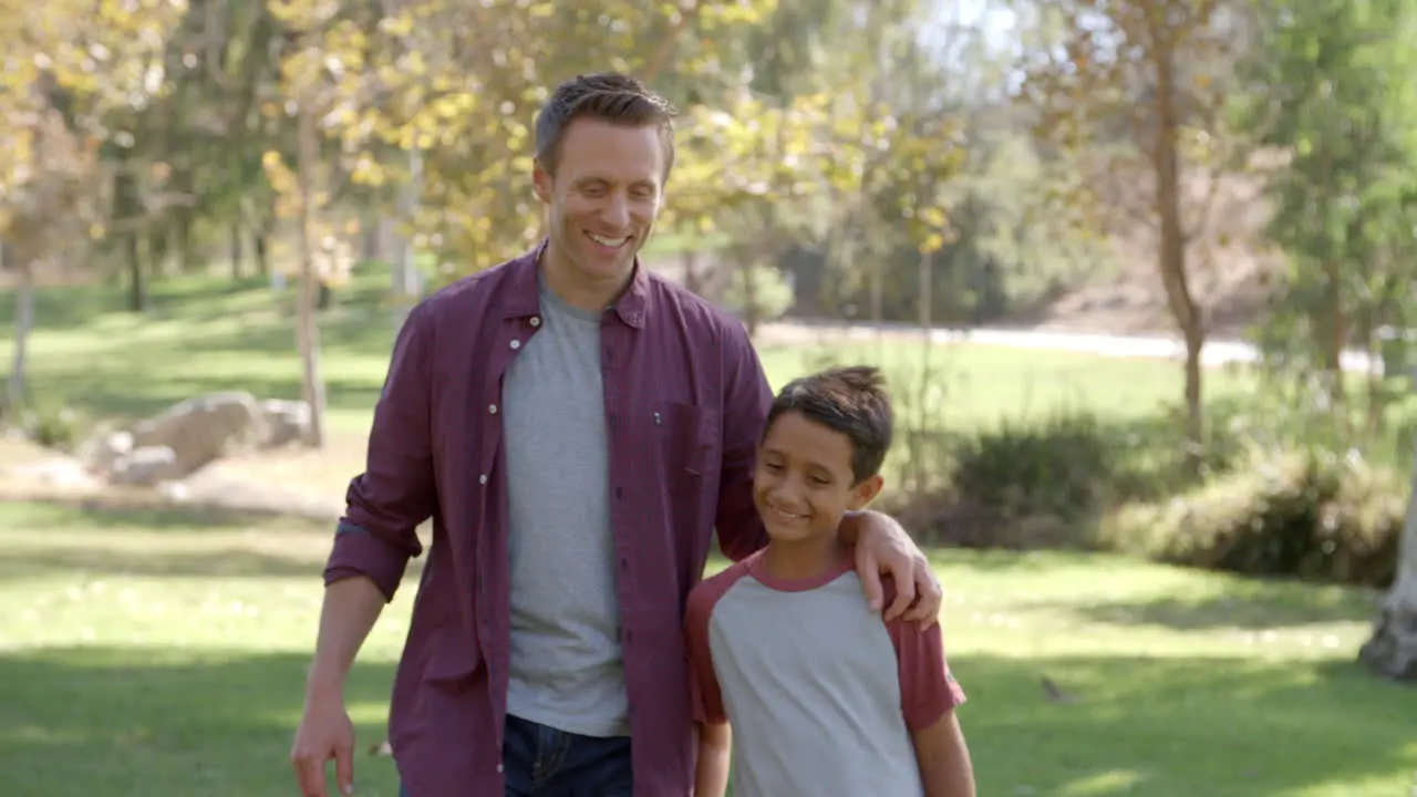 Mixed race Asian boy and father walk in to focus in park