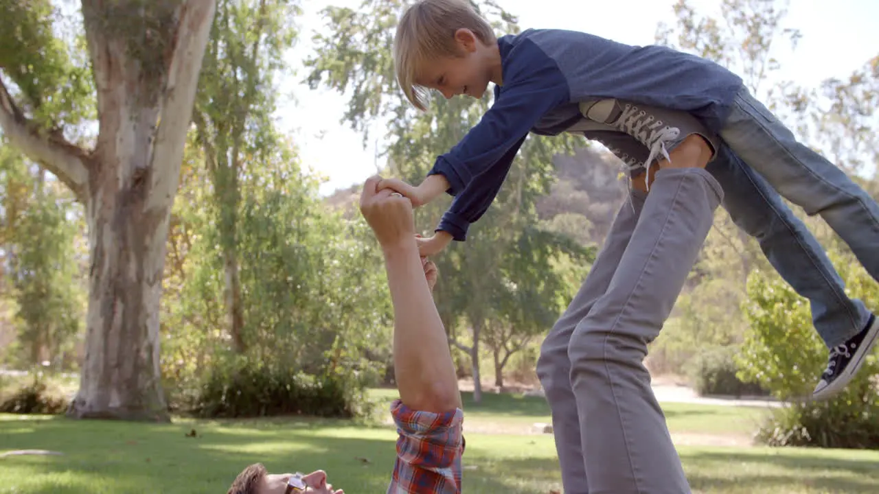 Father and son playing on the grass in a park