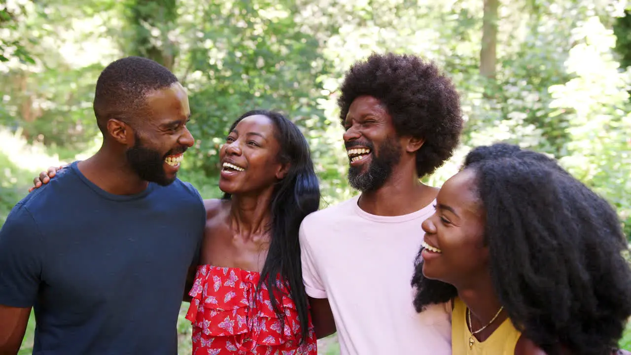 Four black adult friends on a walk in the forest embracing