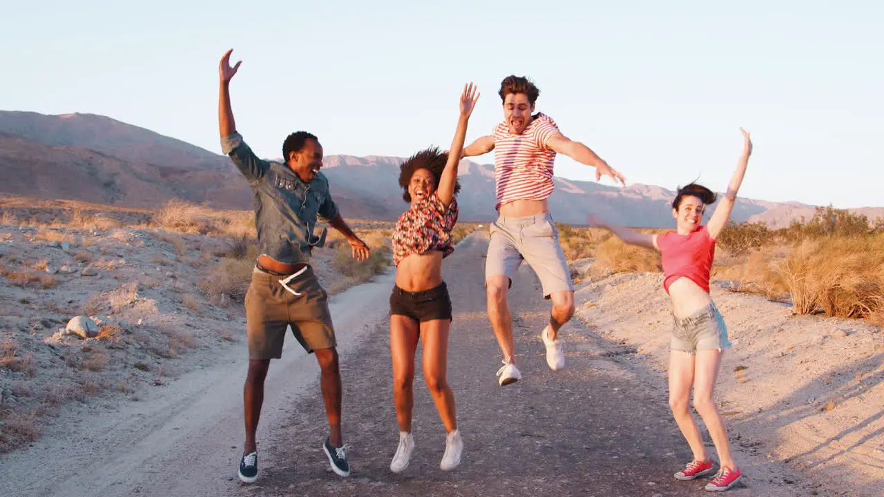 Young adult friends jumping in the air on a desert road