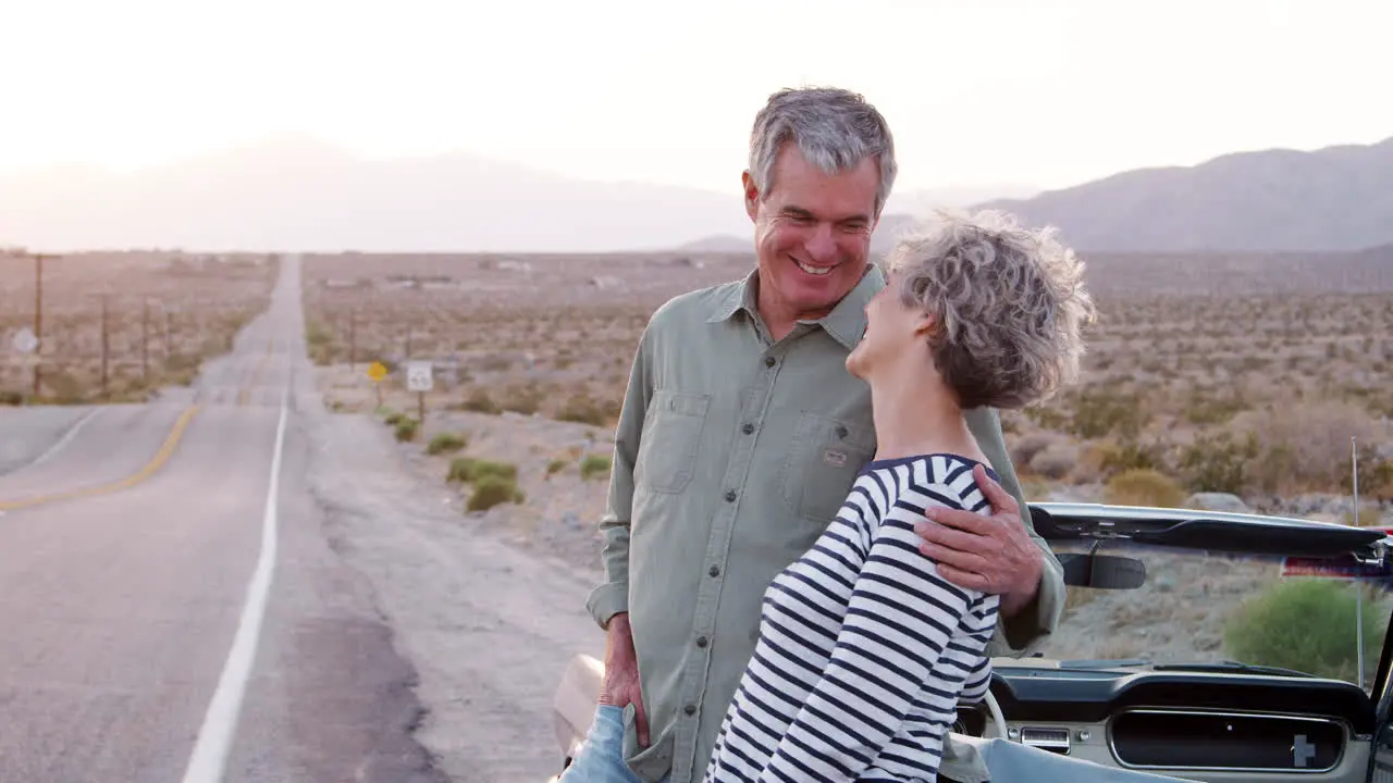 Senior couple standing by car smiling to camera close up