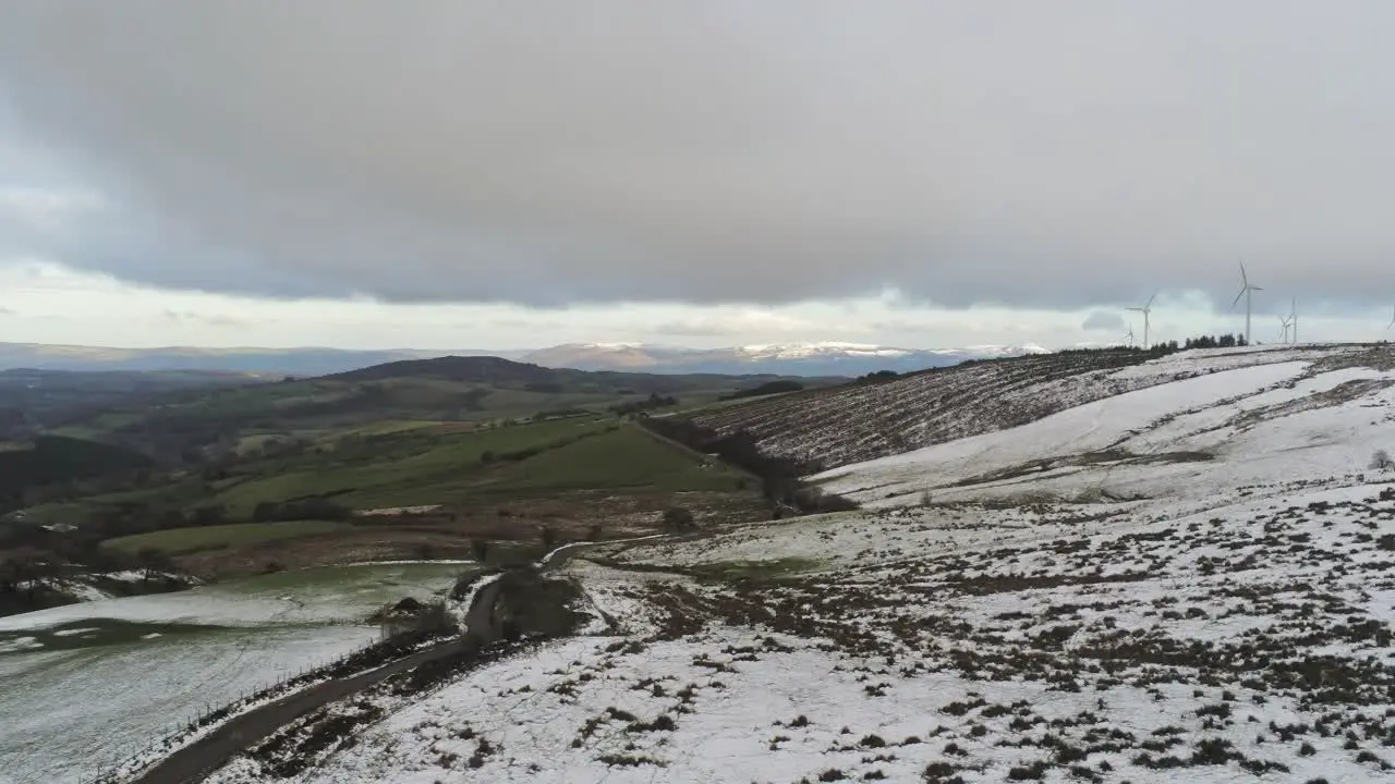 Snowy rural winter valley countryside aerial agricultural farmland landscape left pan shot