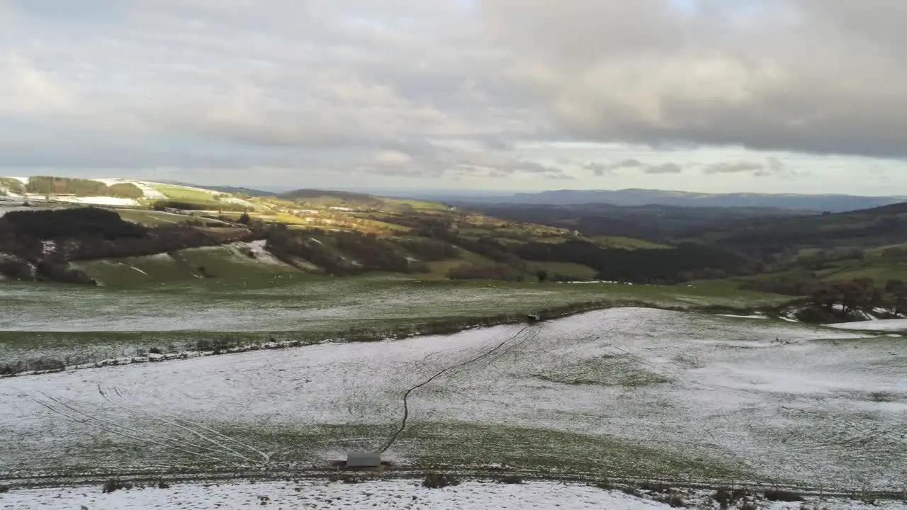 Snowy rural winter valley countryside aerial agricultural farmland moorland left pan descending