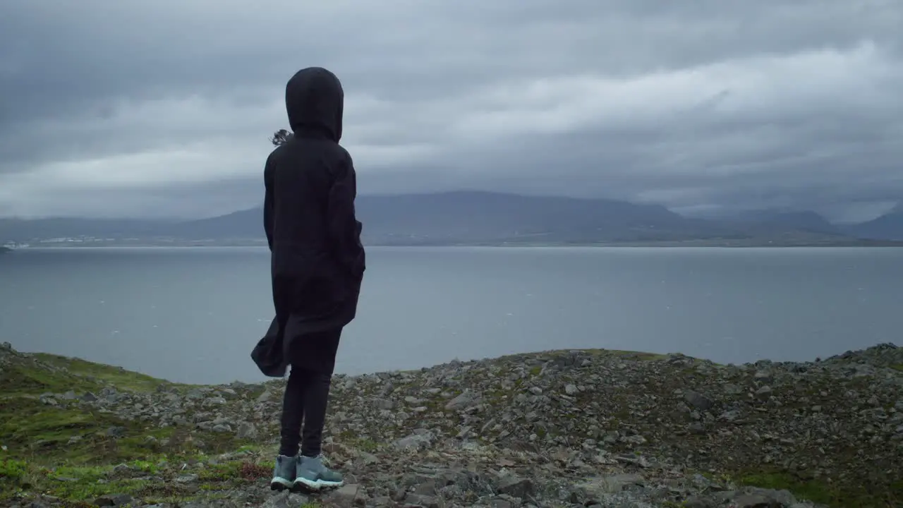 young girl looking at a the landscape on a rainy and windy day