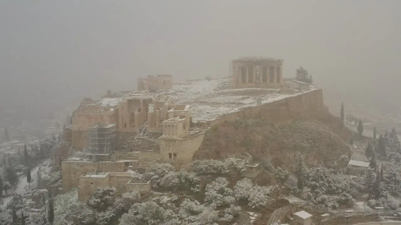 Aerial view away from the Acropolis hill in middle of a blizzard pullback drone shot climate change in Greece