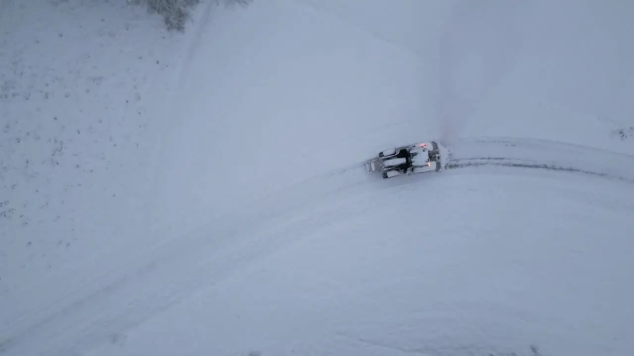 zoom out of a tractor from above plowing snow after snowfall