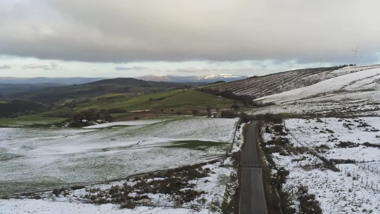 Snowy rural winter distant valley countryside aerial agricultural farmland landscape pan left