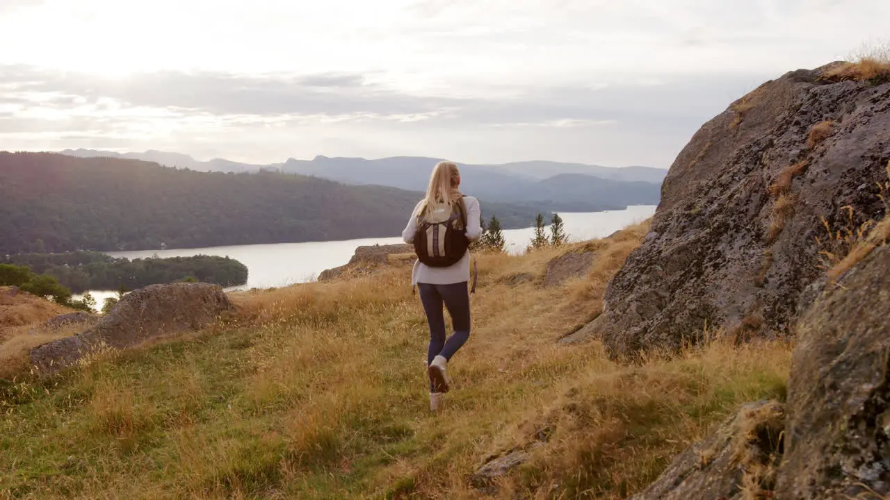 A young adult Caucasian woman stops to admire the view during a mountain hike handheld