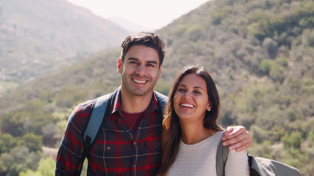 Young smiling couple embracing during a summer mountain hike