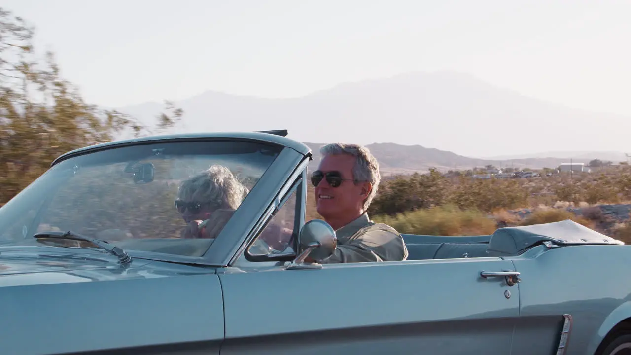 Senior white couple driving classic convertible on highway