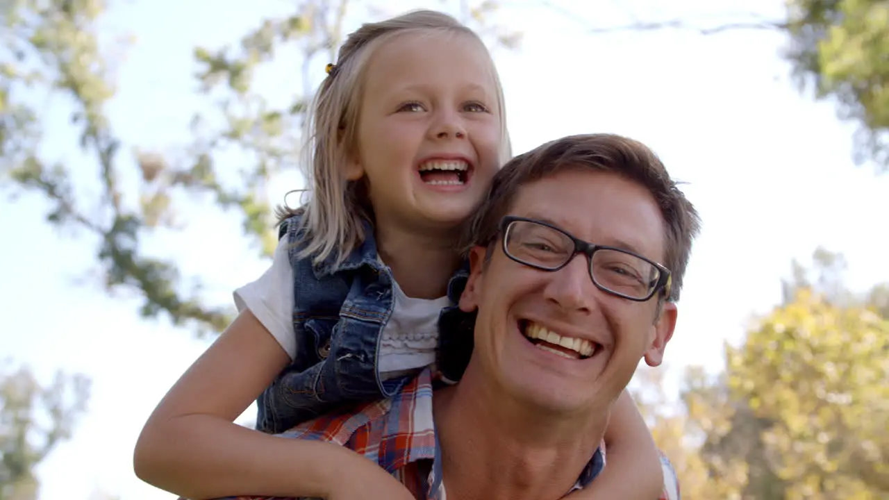 Dad and young daughter pulling faces in a park front view