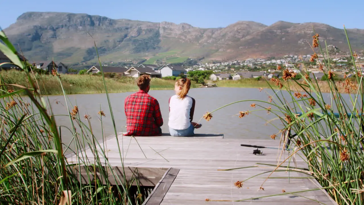 Couple sitting together on a jetty by a lake talking