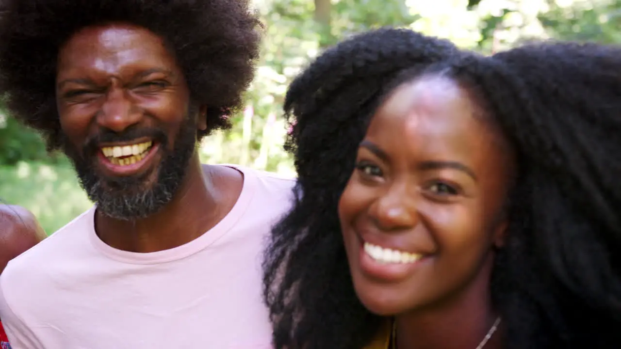 Four black adult friends smile to camera in a forest close up