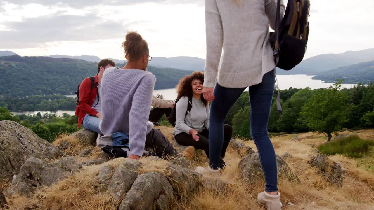 A young adult woman joins her four friends after reaching the summit during a mountain hike  slow motion