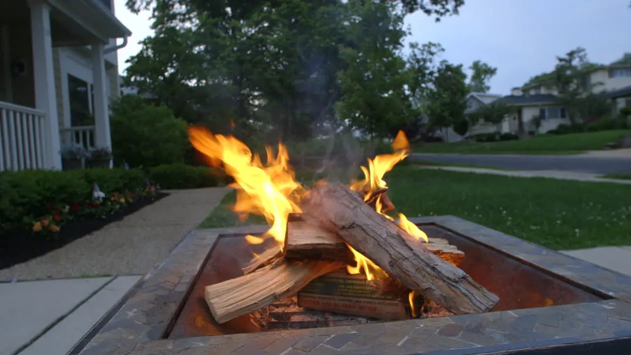 Closeup of wood burning in a fire pit on a driveway in the suburbs on a nice summer evening