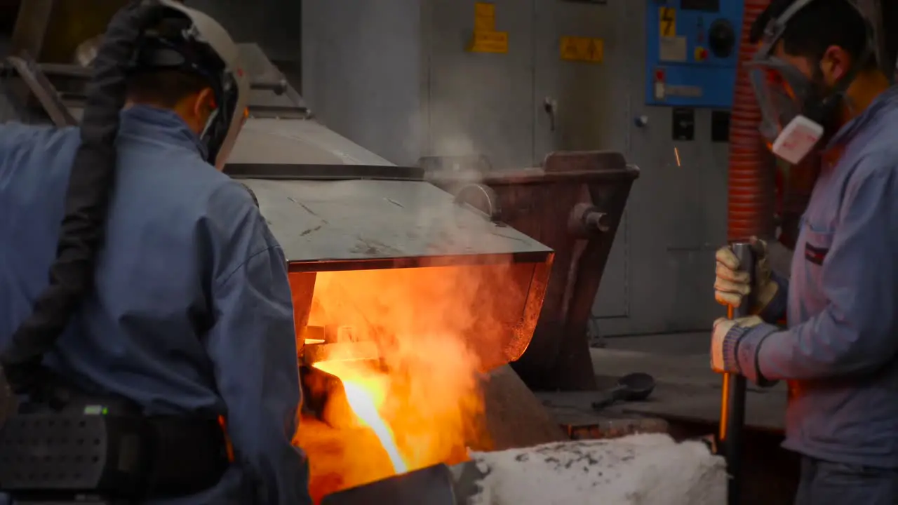 Men pouring liquid metal from furnace hot like fire