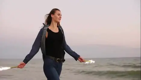 Young beautiful woman running by the sea during sunset and holding burning sparkling candles in both hands Slow Motion shot