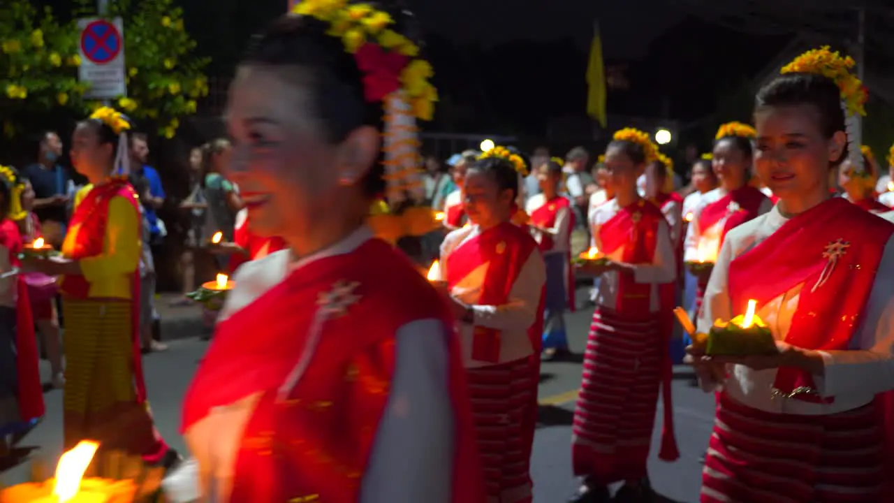 Women in traditional Thai dresses walking during Yi Peng Parade with candles