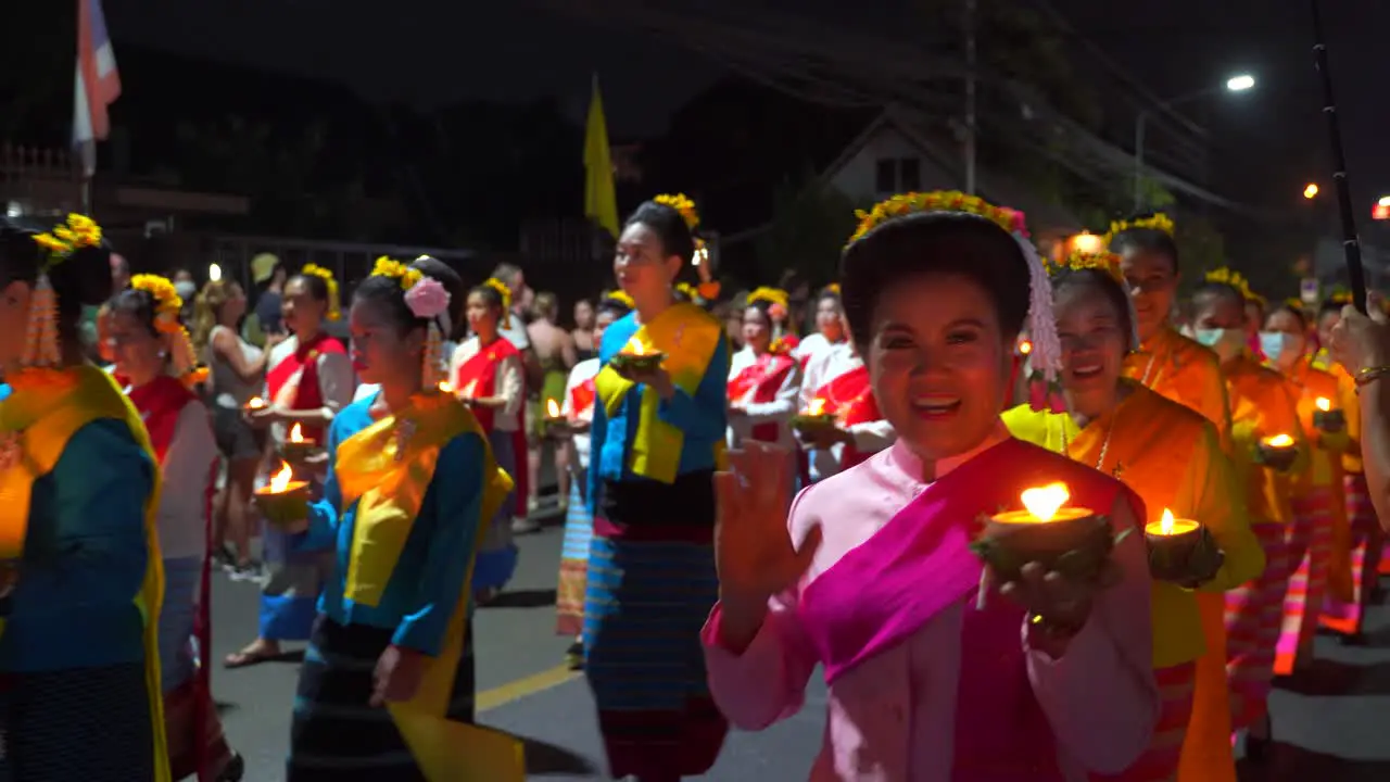 Thai women holding candles during traditional Yi Peng Festival smiling to camera