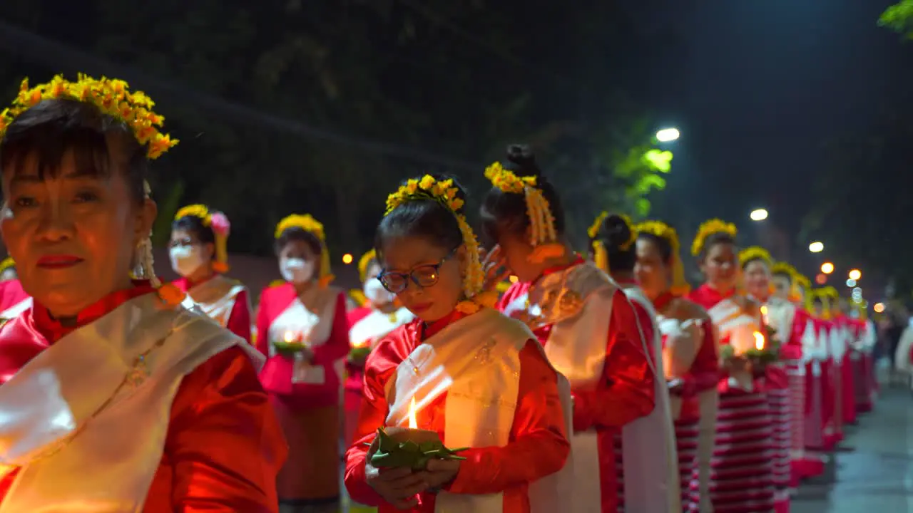 Thai women in traditional dresses holding candles during Yi Peng Festival in Thailand