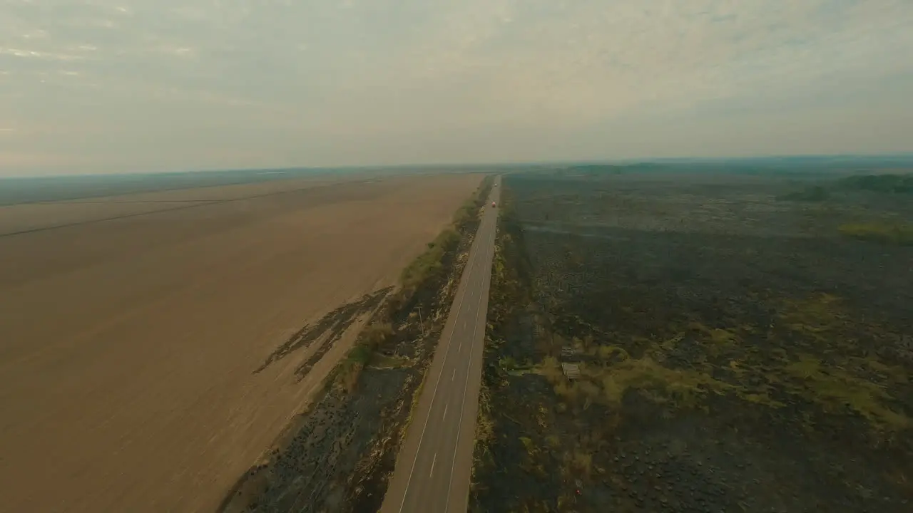 fire next to road truck driving next to smoke clouds farmland cultivation burn-clearing plantation drone aerial overview shot roadside fire shot in 4k