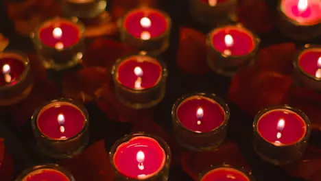 Romantic Lit Red Candles Revolving On Background Covered In Rose Petals