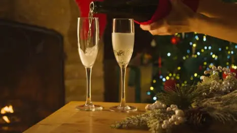 Sliding Close Up Shot of Female Hands Pouring Two Glasses of Champagne From Bottle