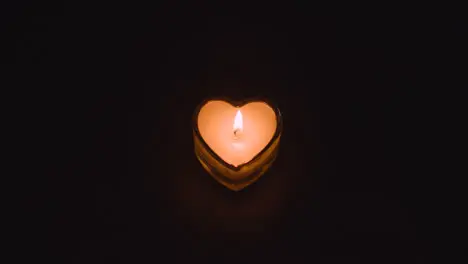 Romantic Lit Heart Shaped White Candle On Black Background Being Blown Out