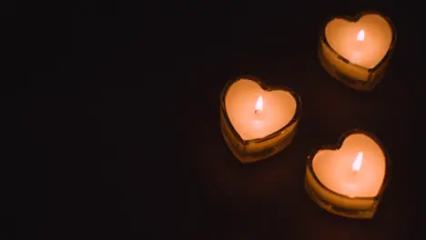 Three Romantic Lit Heart Shaped White Candles On Black Background Being Blown Out