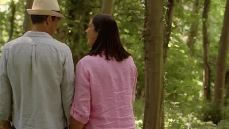 Tracking Shot Following Middle Aged Couple Walking Through Scenic Woodland