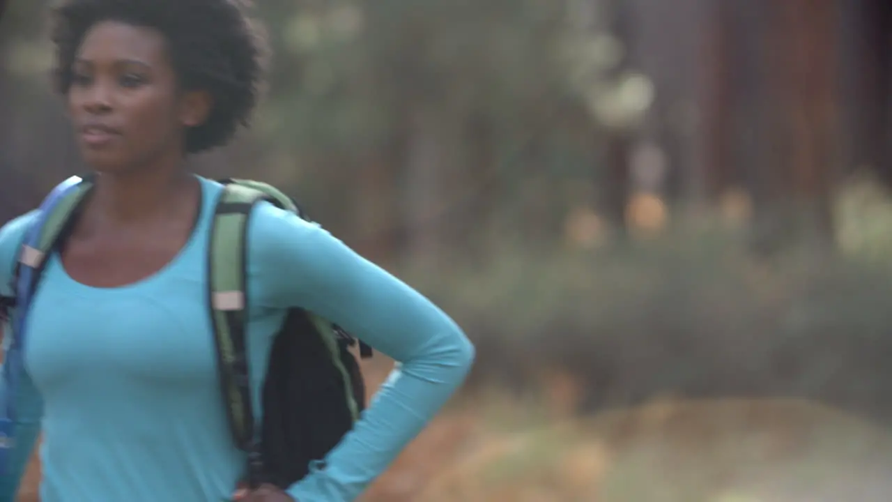 African American woman running in a forest with a backpack