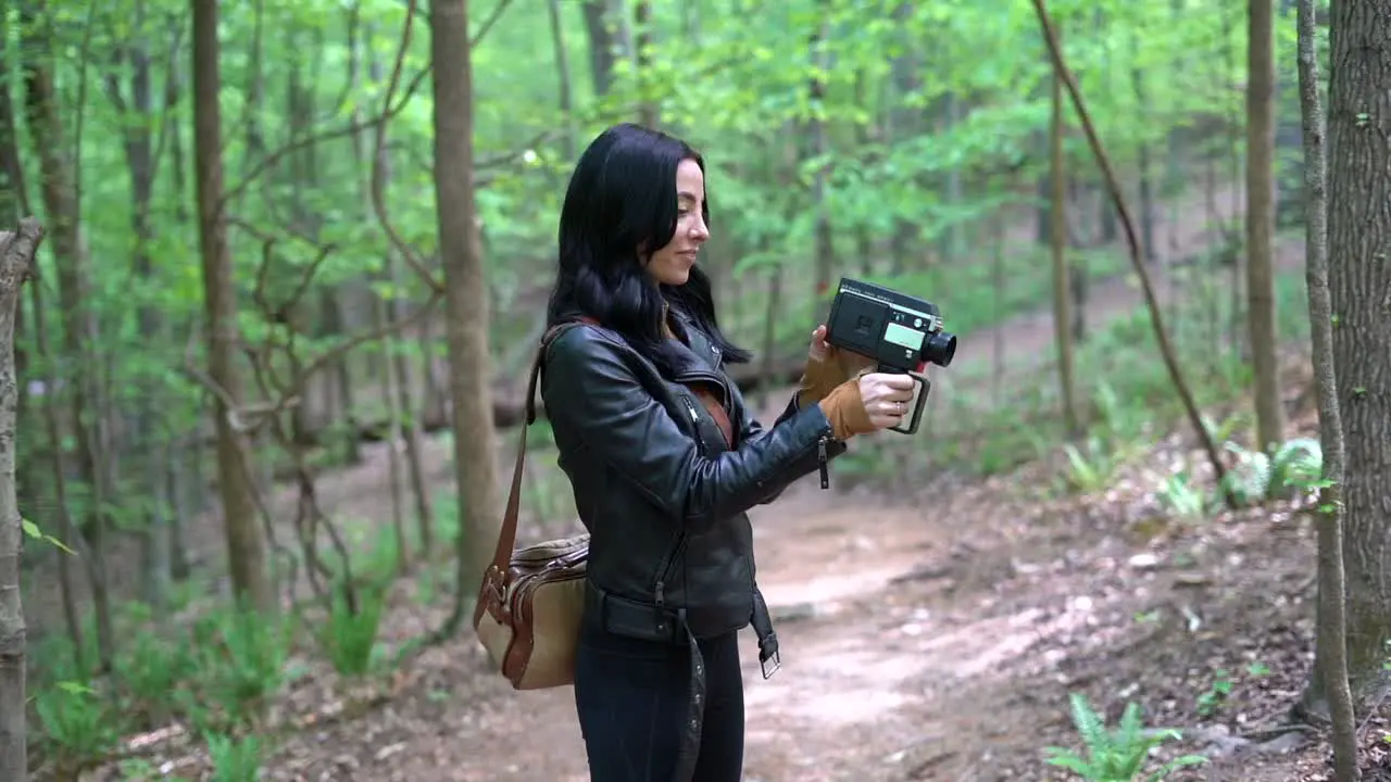 Young attractive woman captivated by an old fashion film camera in the woods during the day concept memories old retro hobby tourist trying new things medium gimbal shot in slow motion