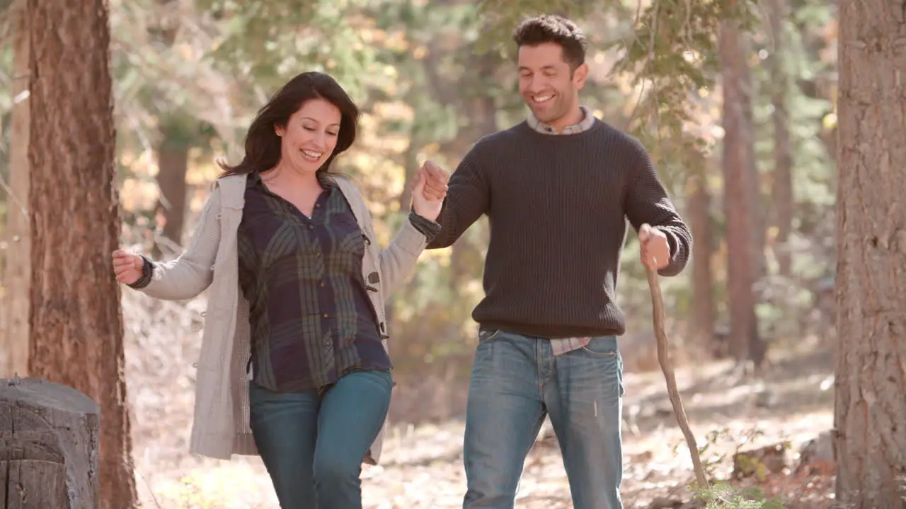 Hispanic couple walk in forest holding hands close up