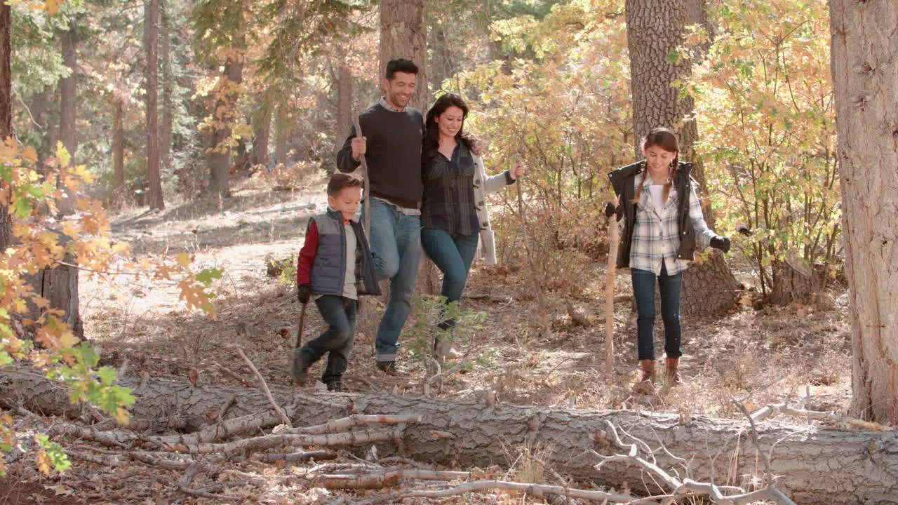 Happy Hispanic family walking in a forest panning shot