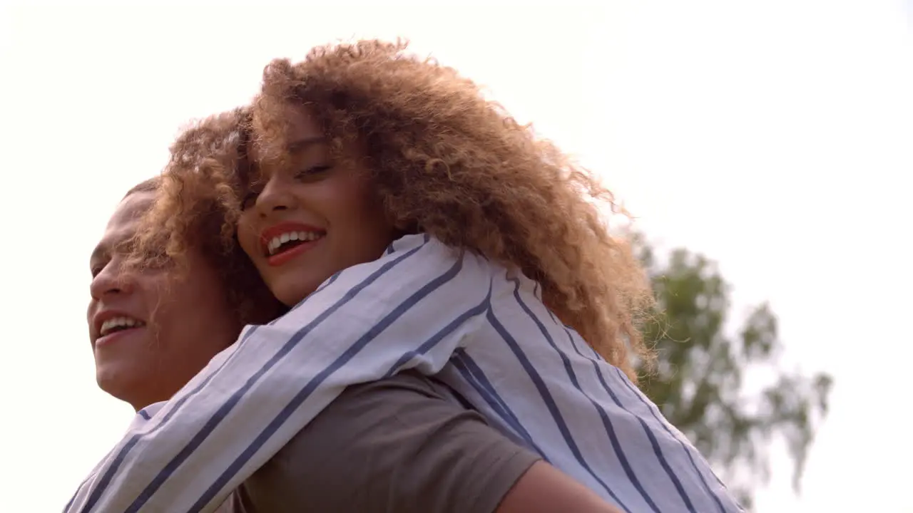 Close up of young adult couple piggybacking outdoors