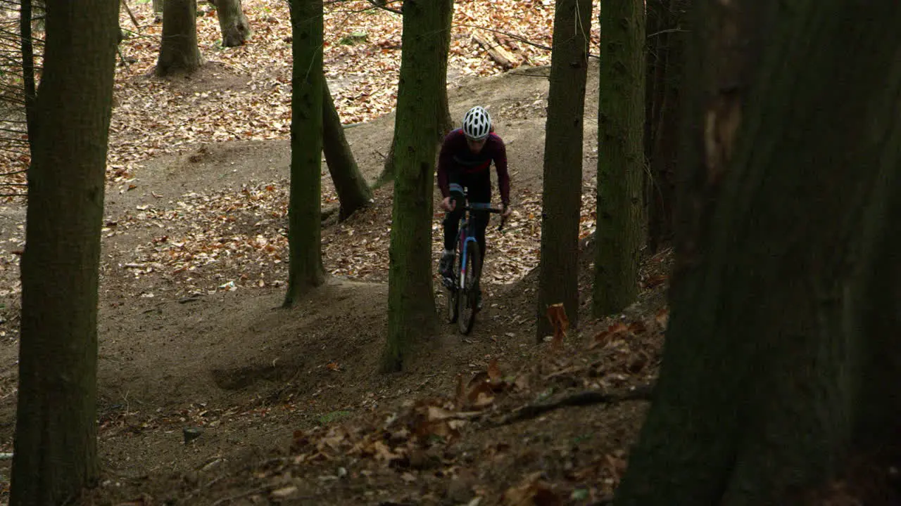 Man climbs forest slope on cross-country cycle front view shot on R3D