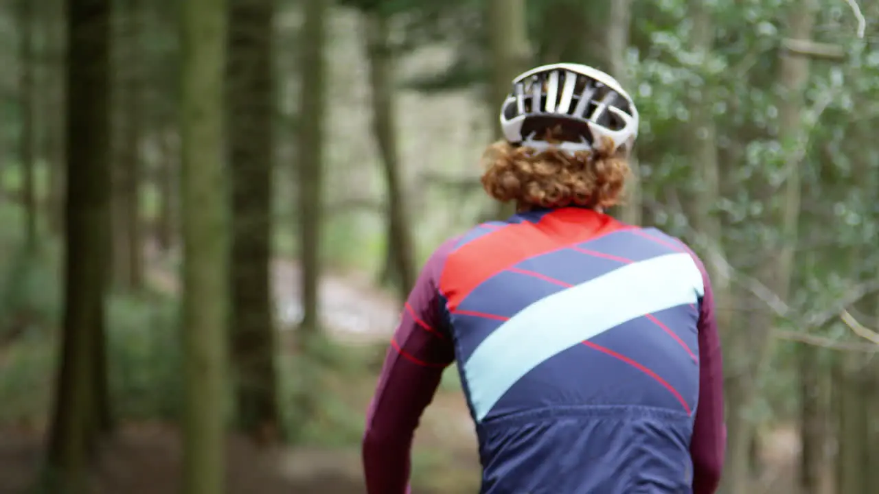 Cross-country cyclist descending a forest slope back view shot on R3D