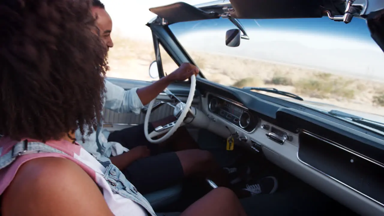 Black couple in open top car on a desert highway close up