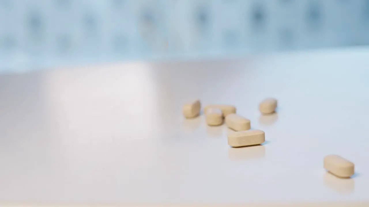 Vitamin tablets falling down on white surface table and bouncing around Shallow depth and motion blur