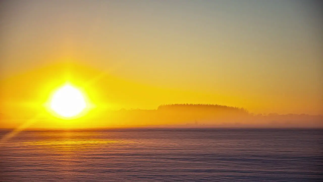 Timelapse shot of beautiful sunset over snow covered agricultural fields with trees in the background during evening time