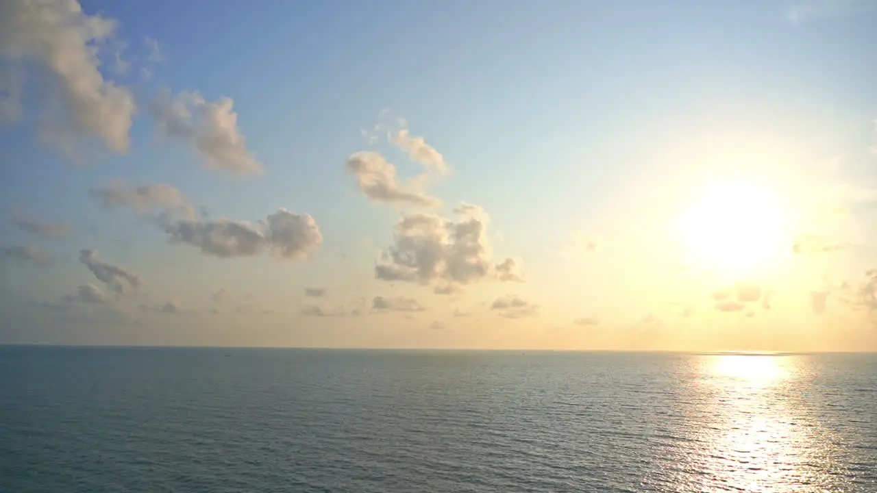 The setting sun hangs in a cloud-filled sky over the ocean