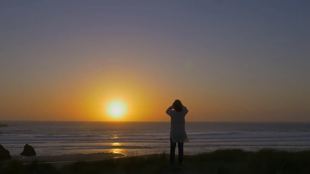 Man in kaftan stares at breathaking sunset over ocean horizon wide