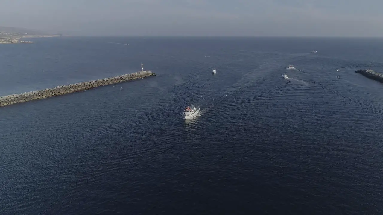 Aerial shot flying towards a white vessel heading into the Newport Bay with birds flying around it in Newport Beach California