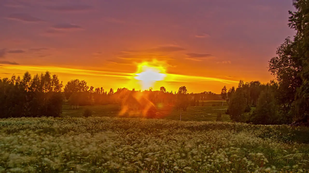 Dramatic sky at sunset with red sun shine over a rural field